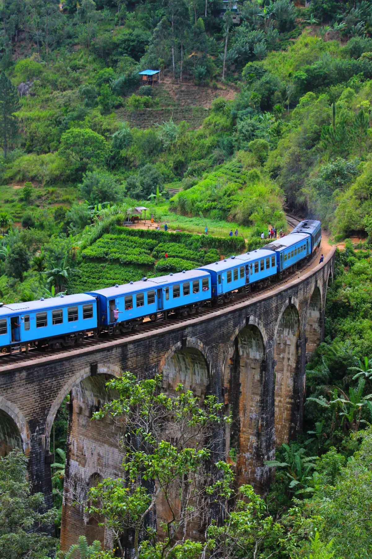 A blue train crossing Nine Arch Bridge in Sri Lanka